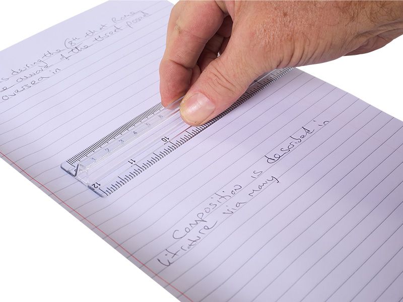Hand using a ruler on a lined notepad