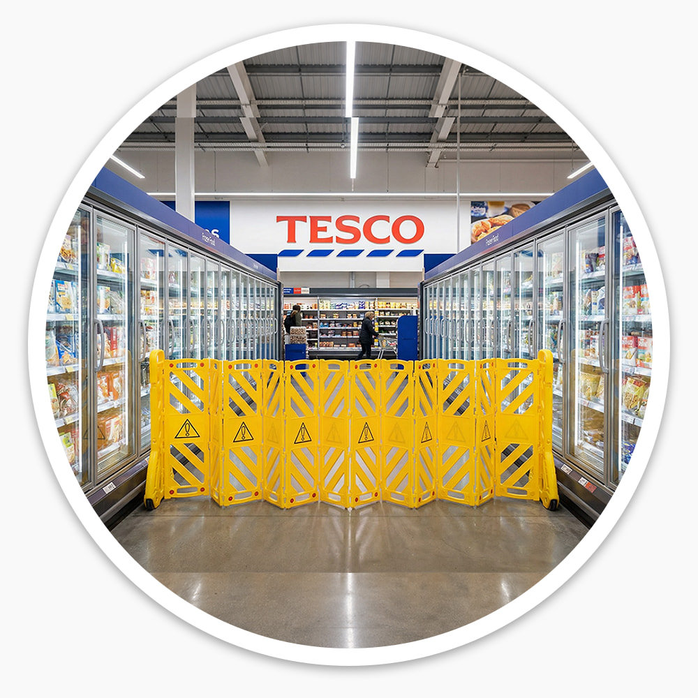 Yellow Portable Expanding Barrier opened across a supermarket freezer aisle