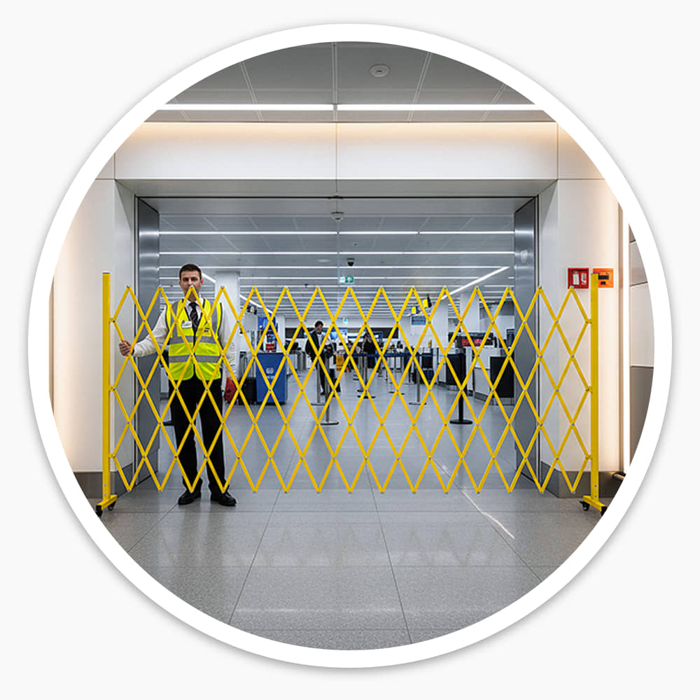 Staff member in hi-vis beside the Large Expandable Barrier, opened across a terminal walkway