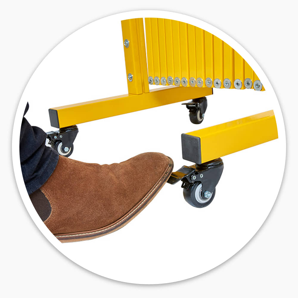 Boot pressing the brake on a castor wheel of the Large Expandable Barrier's yellow steel foot