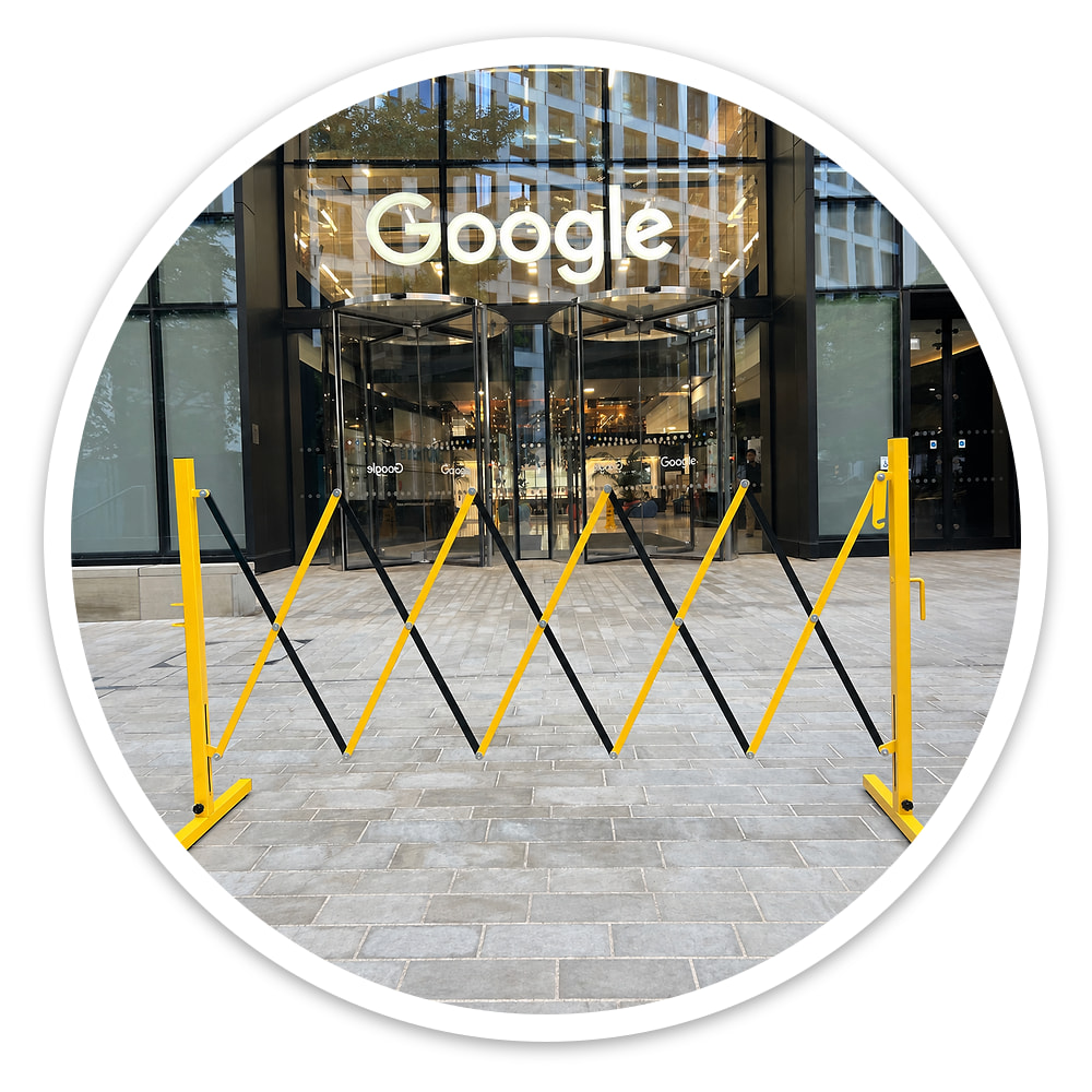 Small Expanding Safety Barrier outdoors in front of an office entrance, with the open lattice clearly visible