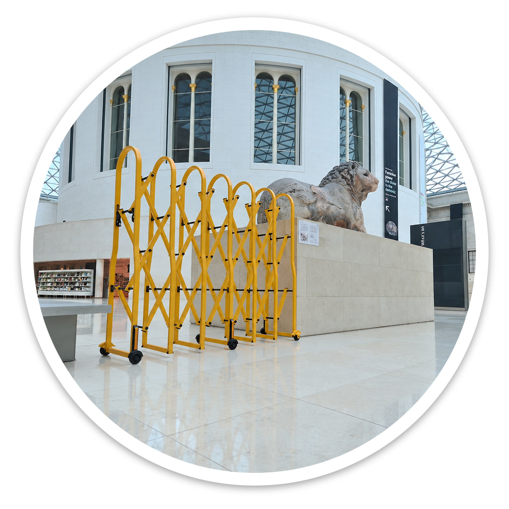 Tall yellow Large Expandable Safety Gate standing in a bright museum hall beside a stone sculpture