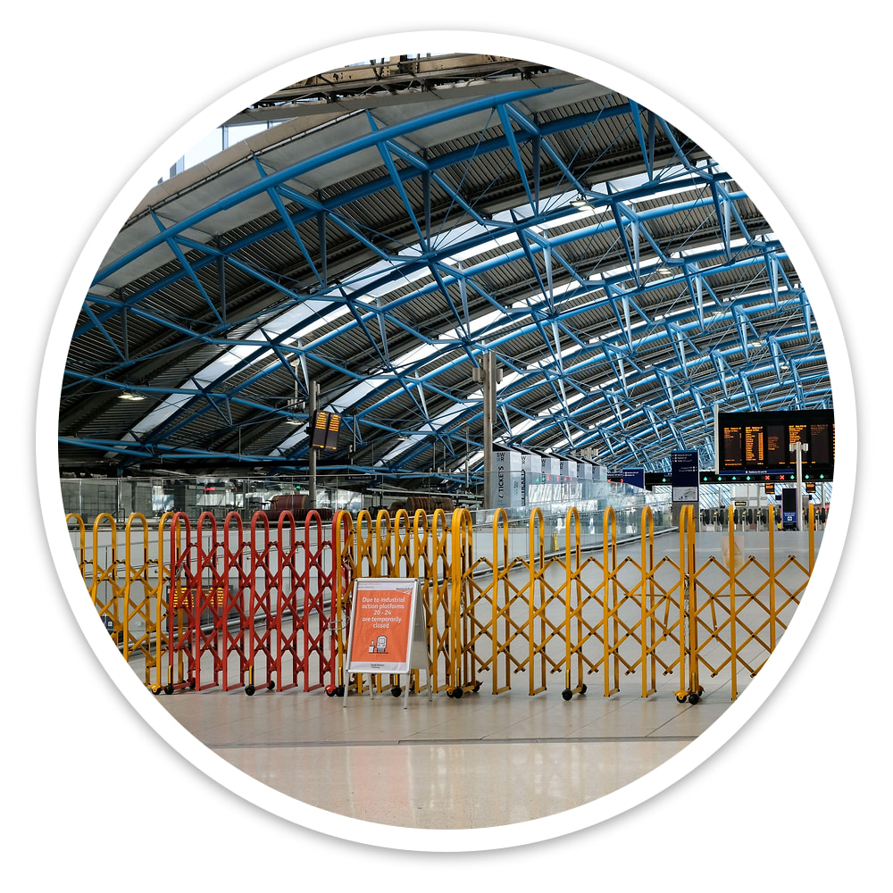 Row of Large Expandable Safety Gates joined across a station concourse beneath a blue steel roof