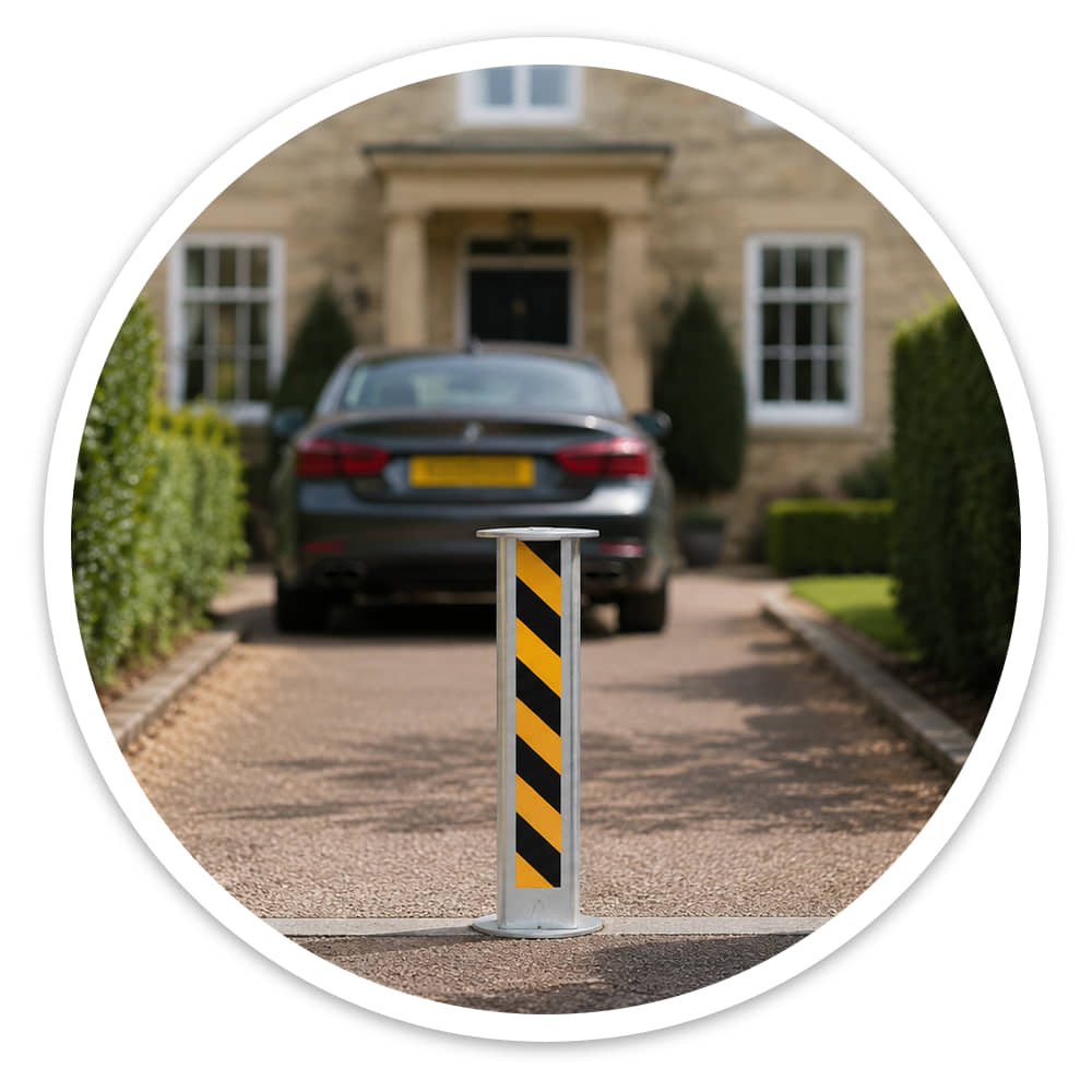 Yellow and black manual rising security post standing raised on a house driveway between brick pillars, with a car parked behind