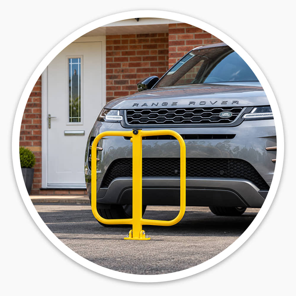 Yellow folding parking barrier raised on a house driveway in front of a grey Range Rover