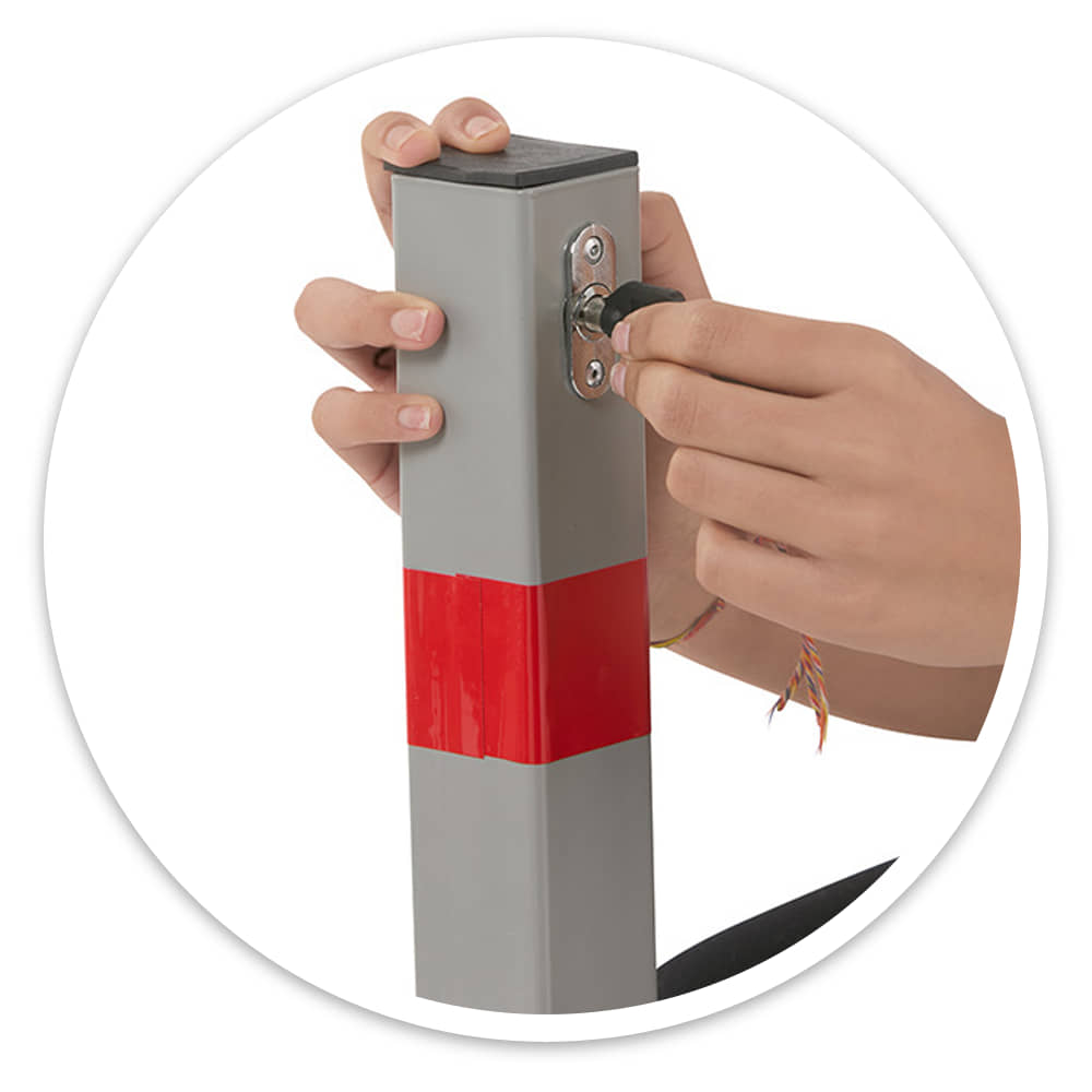 Hand turning a key in the push lock at the top of the folding security barrier