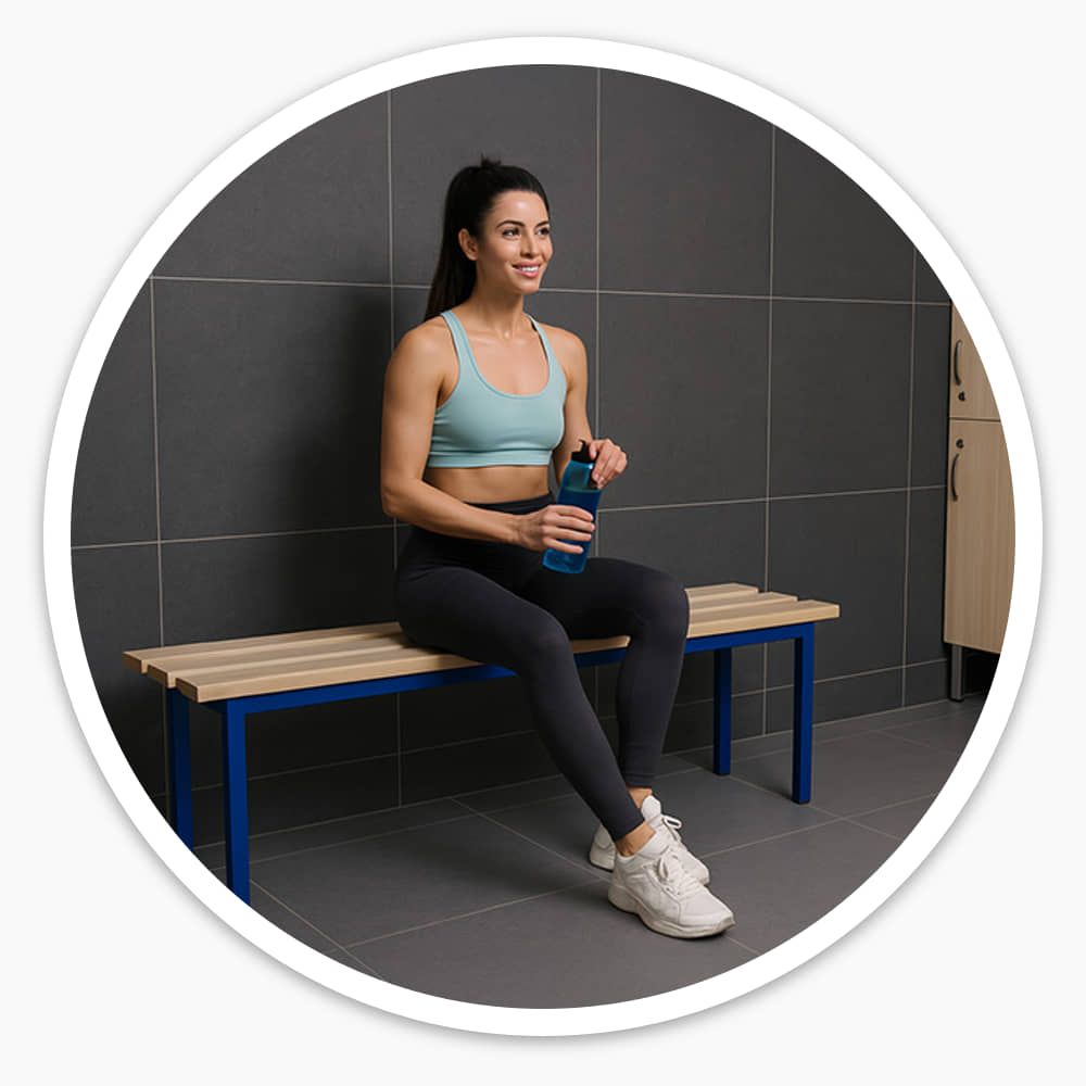 Woman with a water bottle sitting on the 1000mm ash slatted cloakroom bench in a gym changing room by lockers