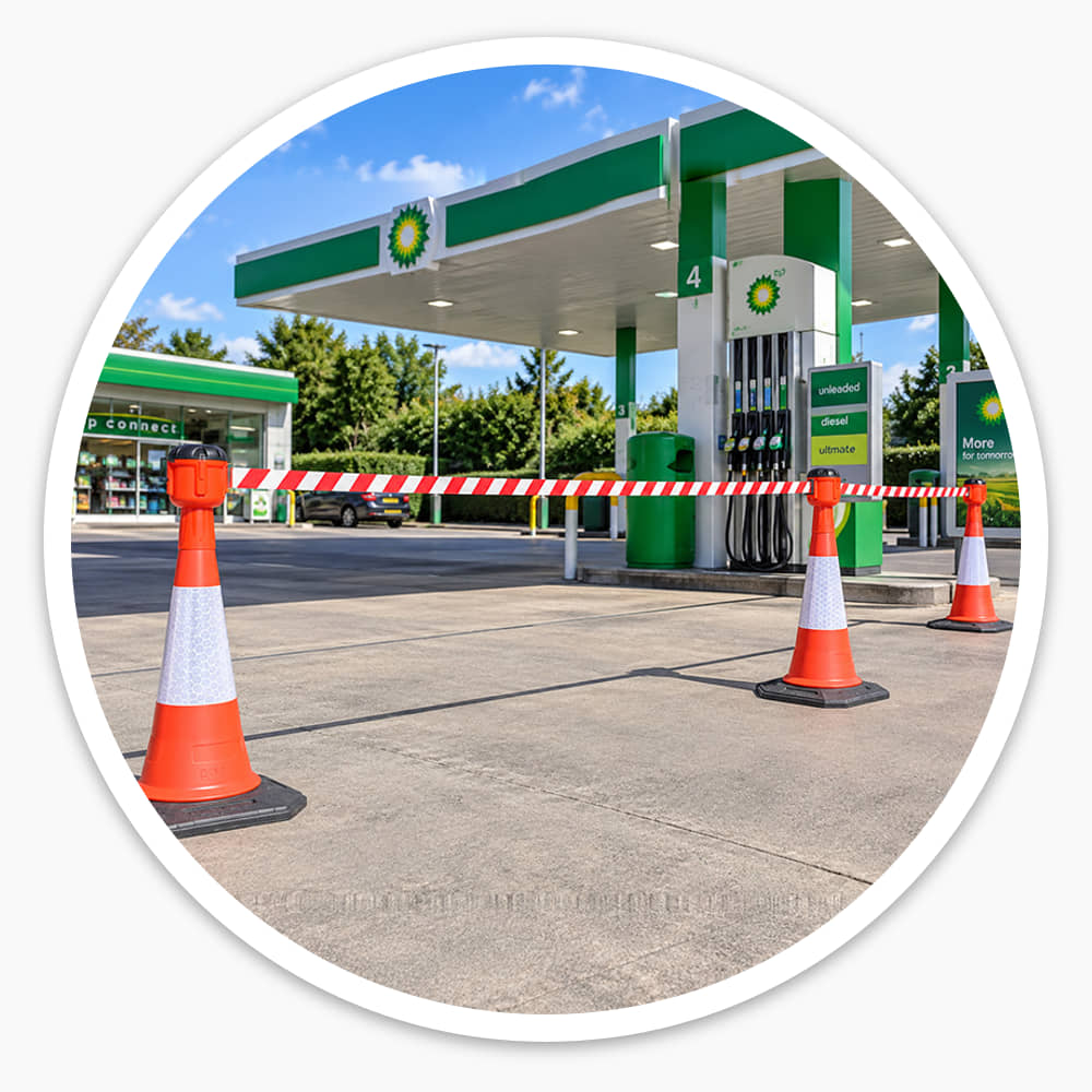 Long red and white cone barrier belts closing off a lane on a petrol station forecourt