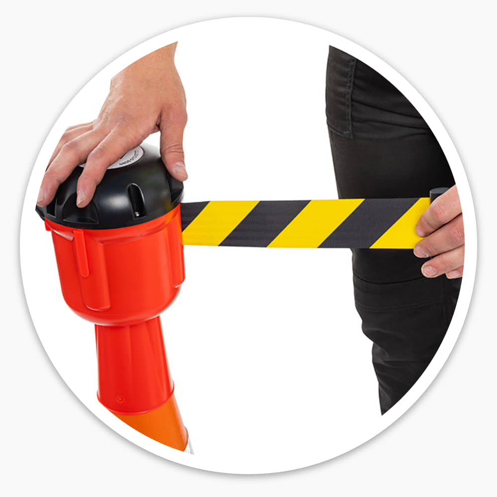 Hand holding the cone barrier topper while the yellow and black belt is pulled out of its cassette