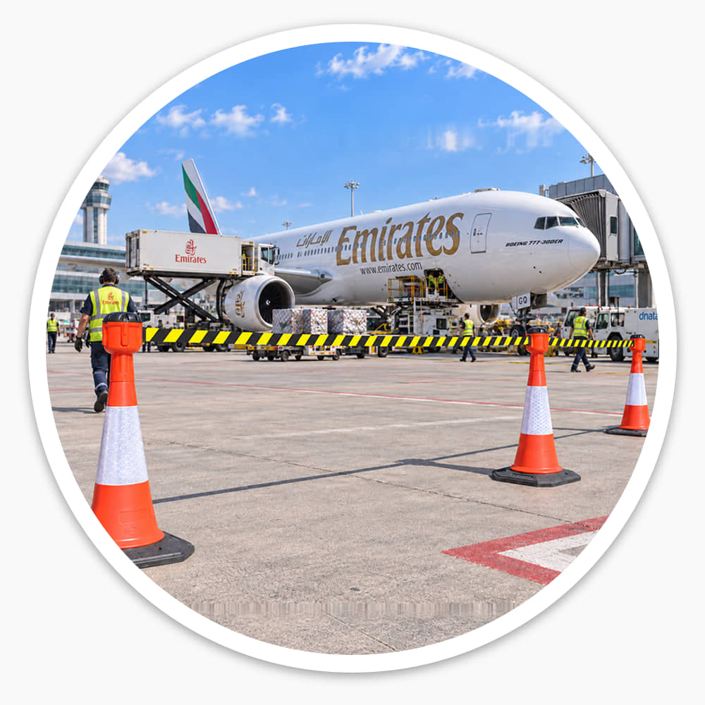 Three cones with retractable cone barrier toppers cordoning off an airport apron beside an aircraft