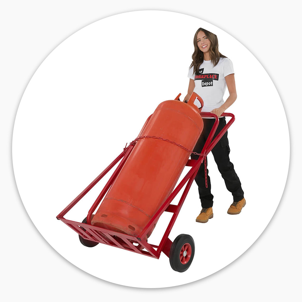 Woman wheeling a red steel Double Gas Cylinder Trolley carrying a large orange gas cylinder held on with a chain