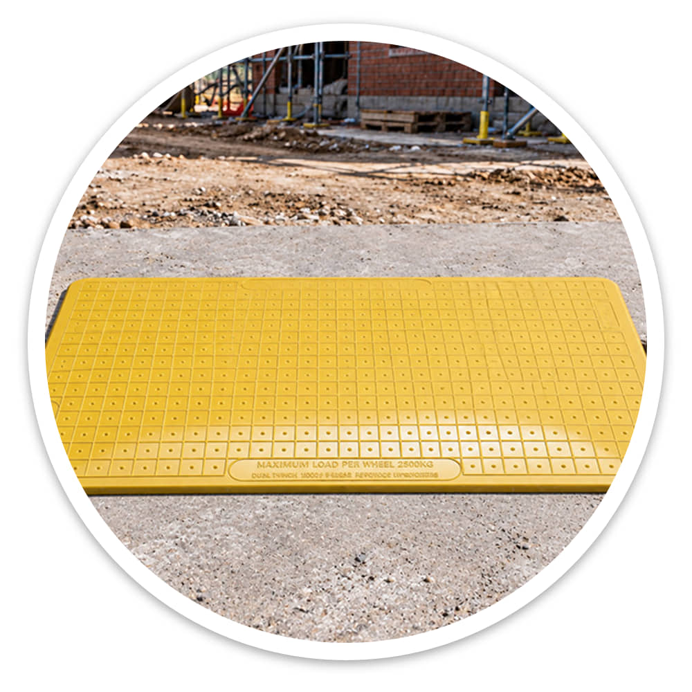 Yellow one-piece composite Pedestrian Hole Cover laid across a trench on a housing construction site