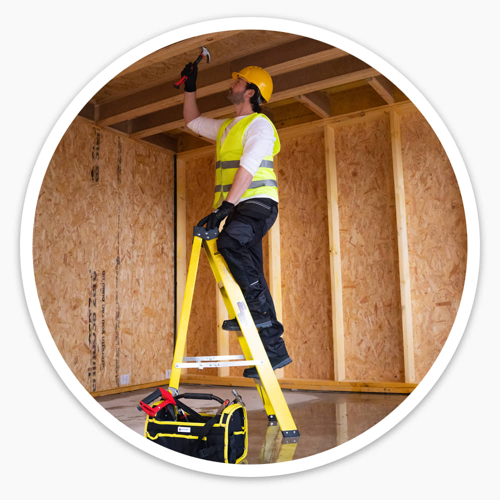 Contractor in hi-vis working overhead from the 4 Tread Fibreglass Step Ladder on a timber-framed site