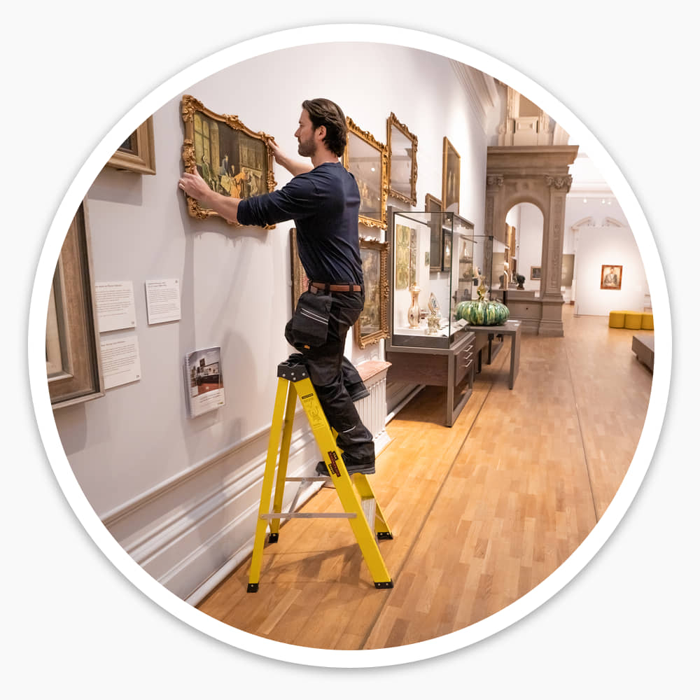Worker on the 4 Tread Fibreglass Step Ladder adjusting a framed painting high on a gallery wall