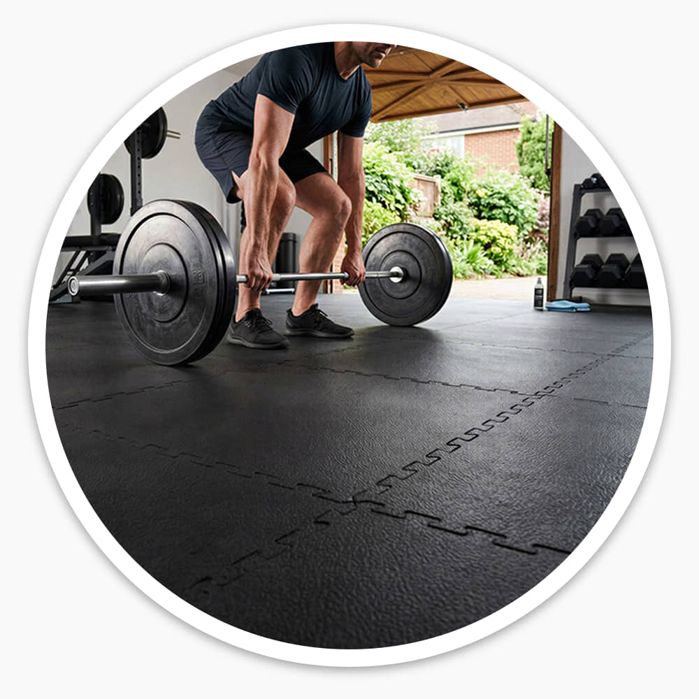 Man lifting a loaded barbell in a garage gym floored with black Fine Grain Interlocking Gym Floor Tiles