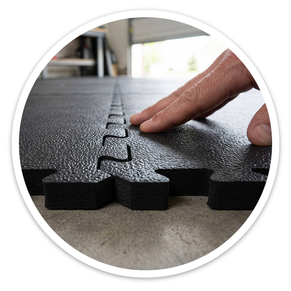 Hand pressing together the jigsaw join of two black Fine Grain Interlocking Gym Floor Tiles on concrete