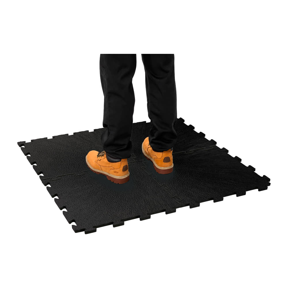 Person in work boots standing on four joined Fine Grain Interlocking Gym Floor Tiles in black vinyl, on white