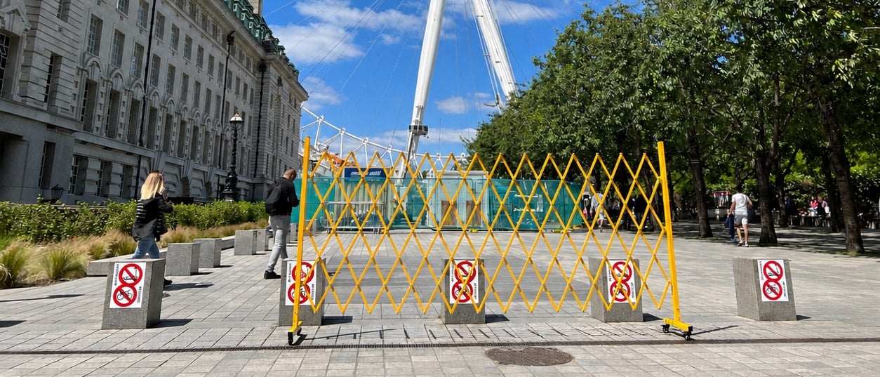 Large Expandable Barrier fully opened across a wide paved walkway outdoors, closing off a work zone